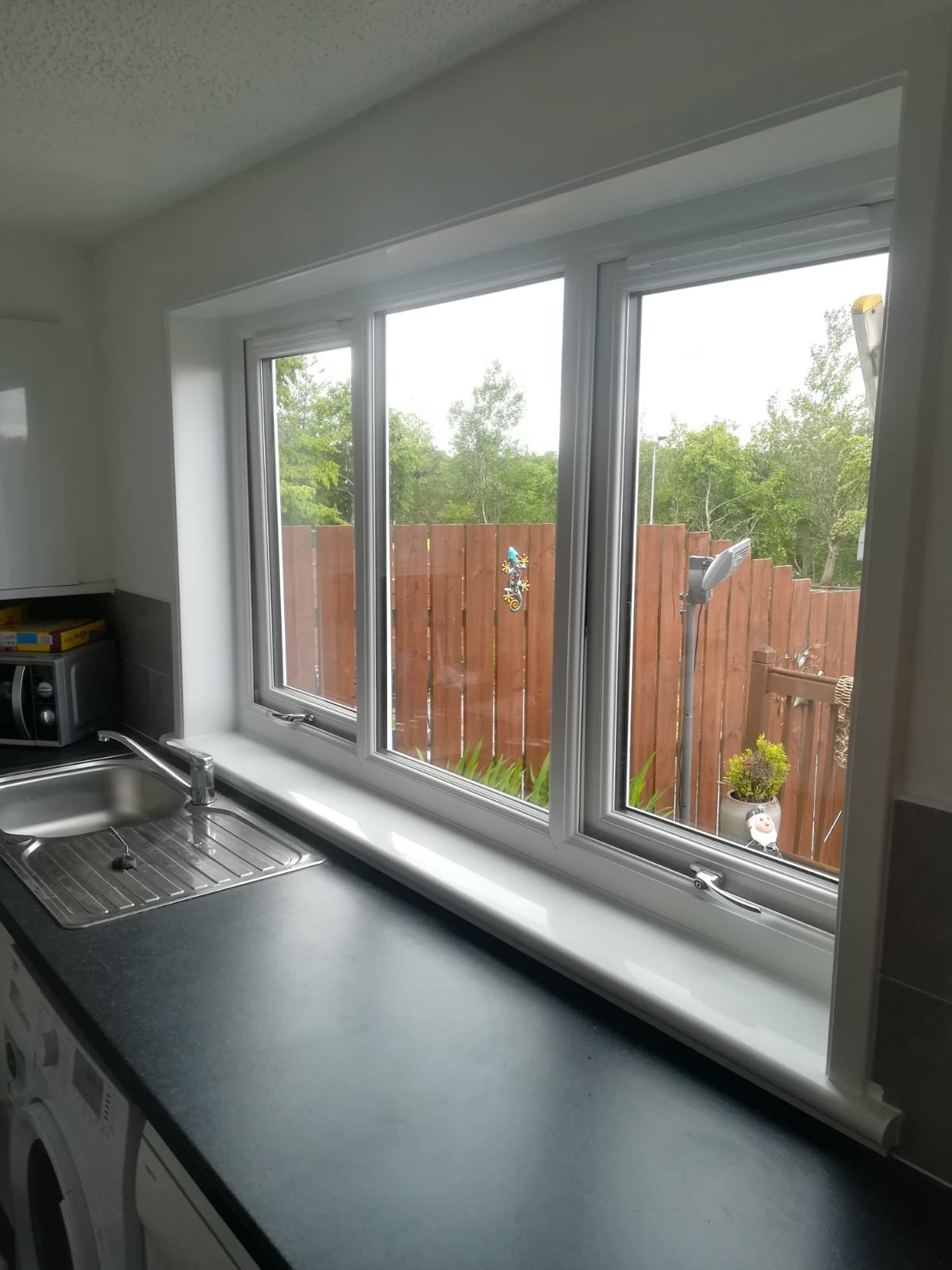 Triple white uPVC kitchen window above worktop with garden view